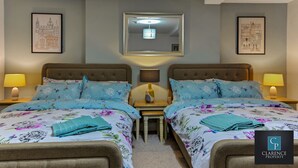 A twin bedroom with two beds, a nightstand with lamps, and framed pictures on the walls. - Crawford Apt (Londonderry)