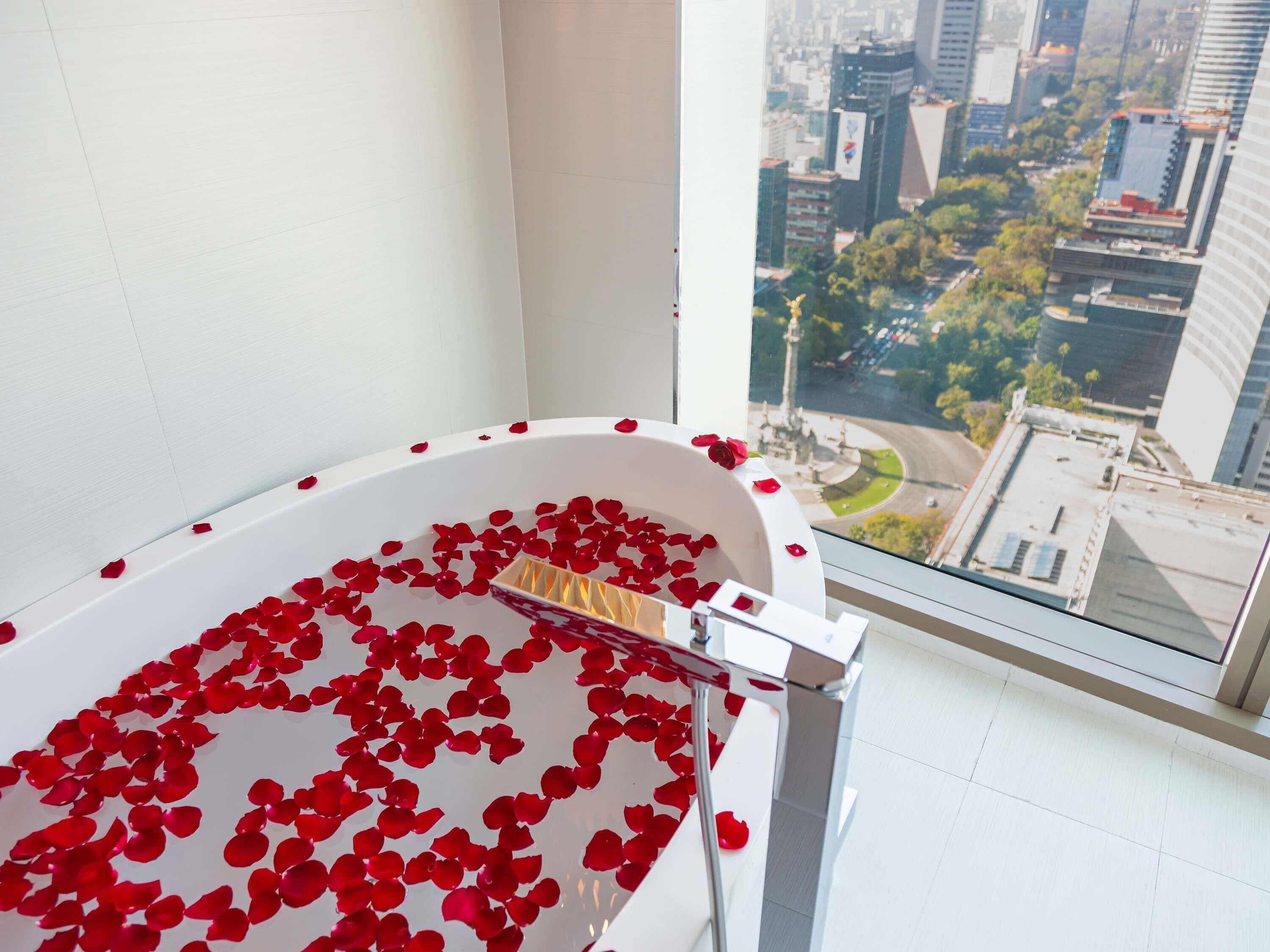 Une baignoire remplie de pétales de rose, avec vue sur la ville.
