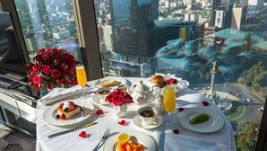 Una mesa preparada para el desayuno, un ramo de rosas rojas y vistas de la ciudad.