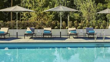 En säsongsöppen utomhuspool och solstolar