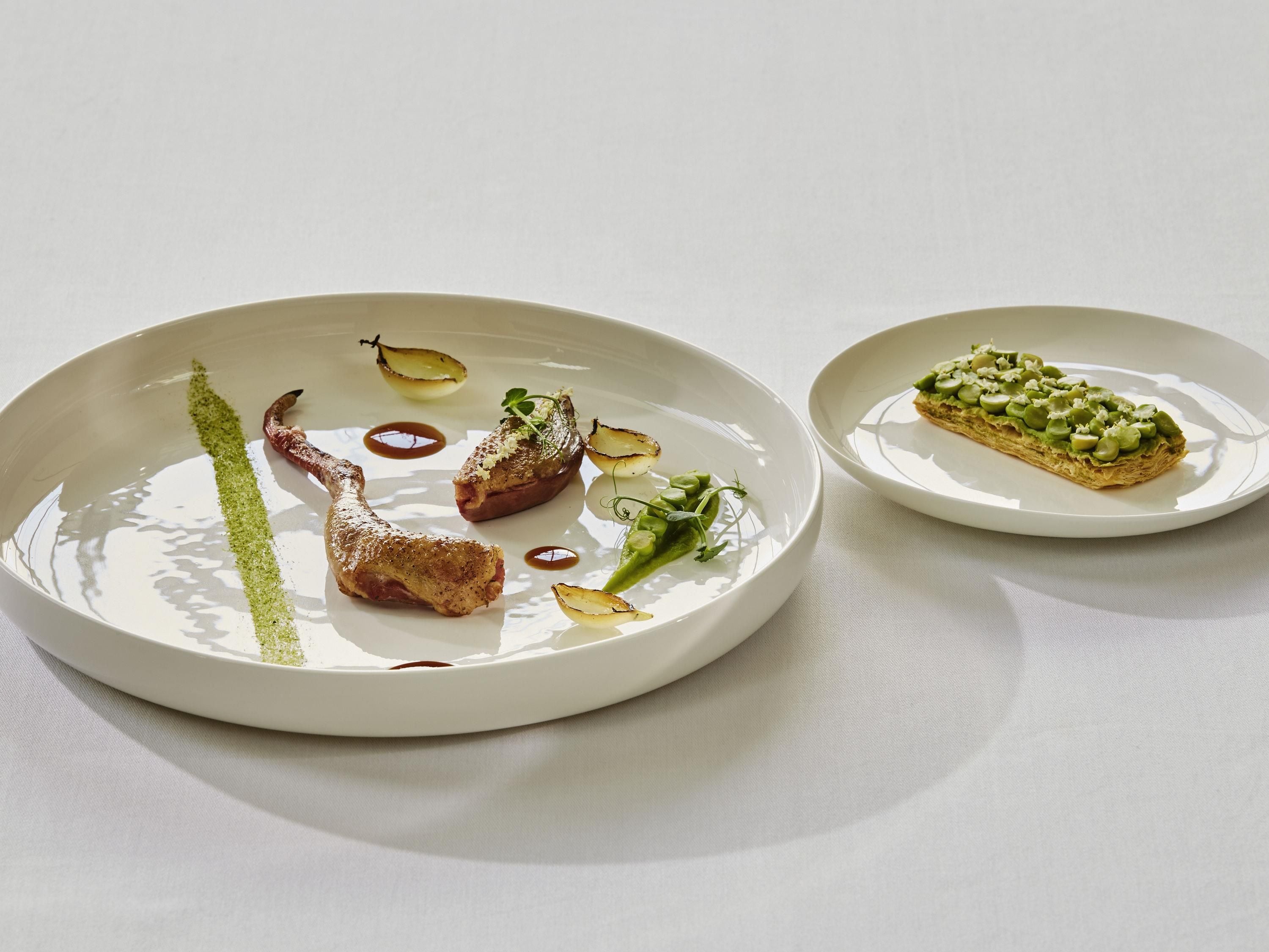 Un plato blanco con comida y un plato más pequeño con un pastel.
