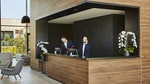 Un mostrador de recepción con dos empleados, diseño interior moderno y vistas al exterior.