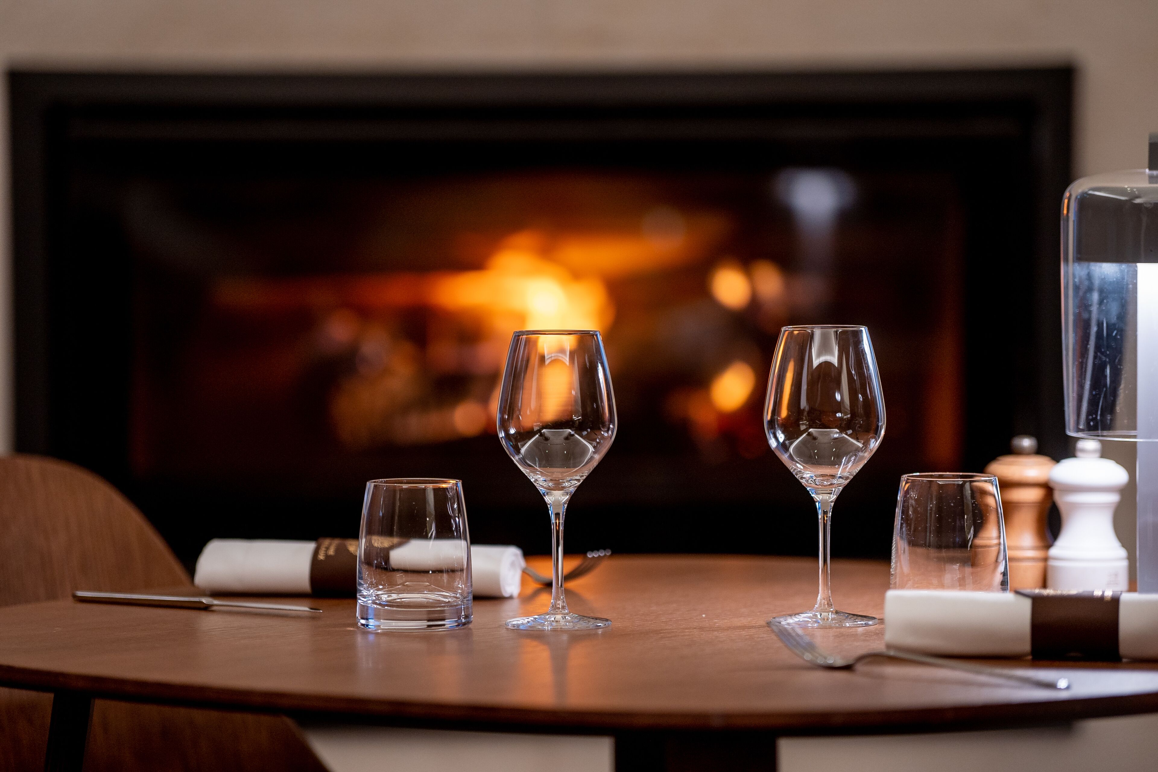 A table with three wine glasses and a knife, set against a background of a fireplace.