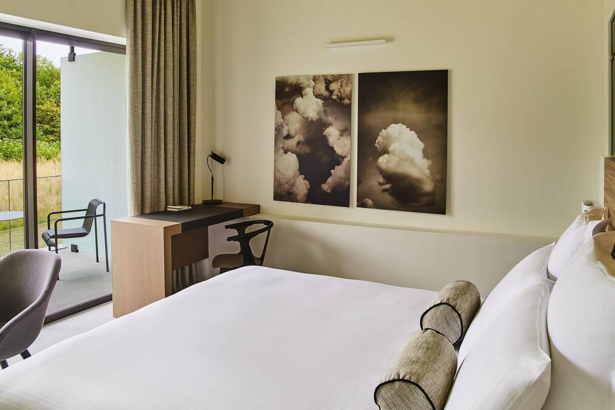 Ein Hotelzimmer mit einem Bett, einem Schreibtisch, einem Stuhl und einem großen Fenster.