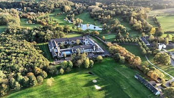 Vue aérienne d’un terrain de golf avec un club-house, entouré d’une végétation luxuriante et d’arbres.
