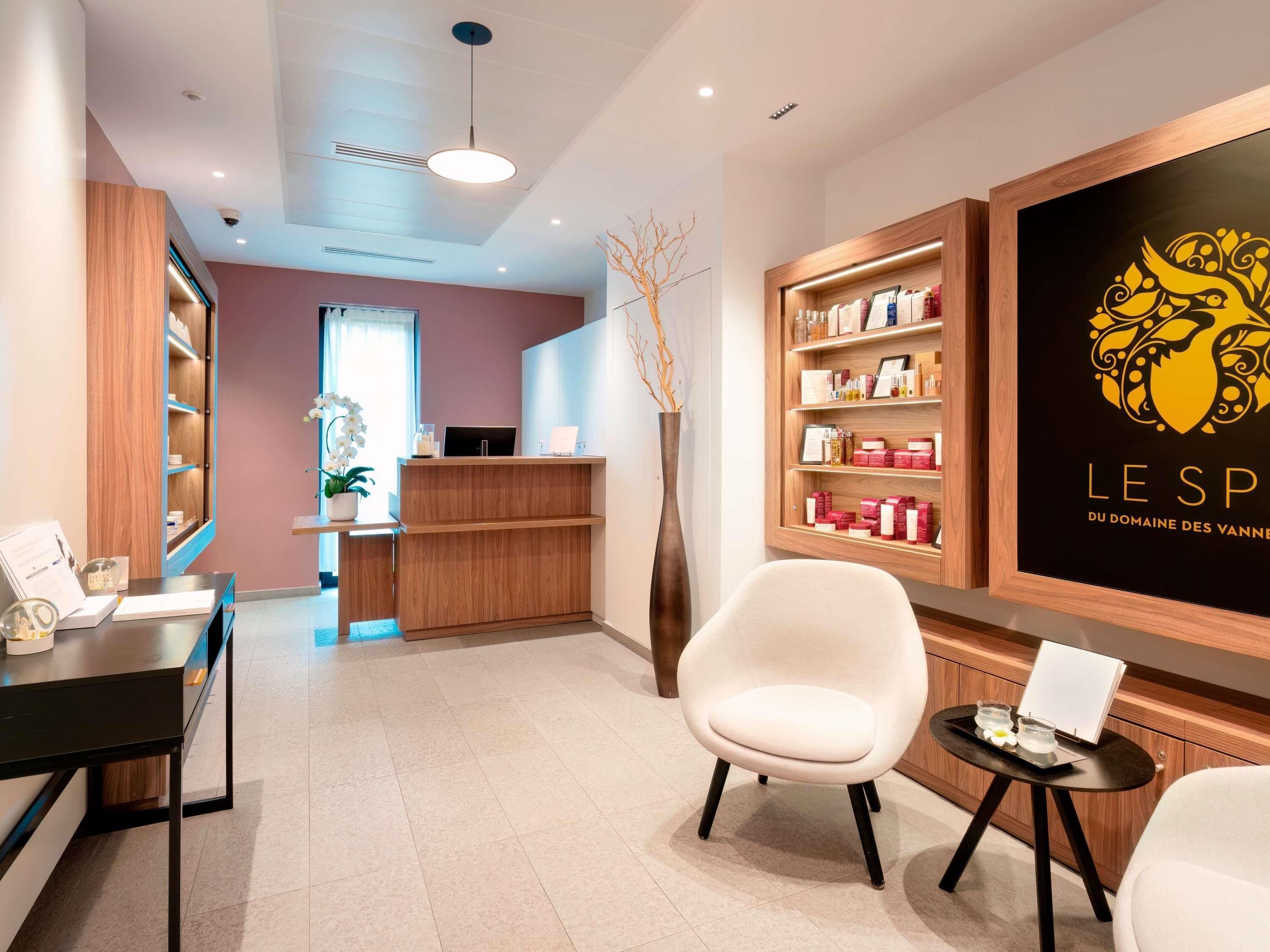 Una moderna zona de recepción con un mostrador de madera, una silla blanca y una estantería llena de productos.