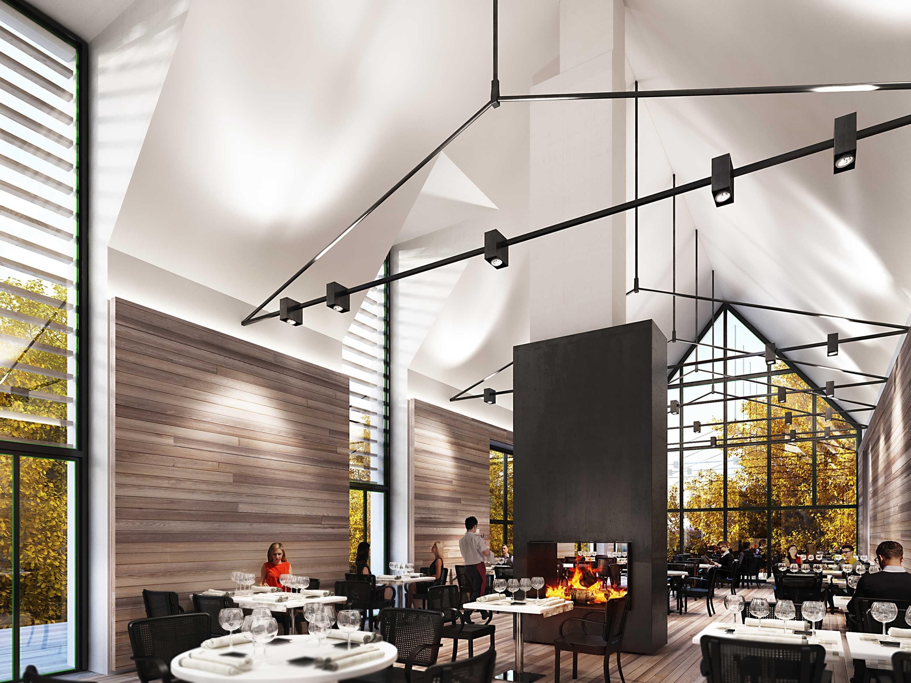 Un restaurante moderno con techos altos, paneles de madera y una chimenea central.