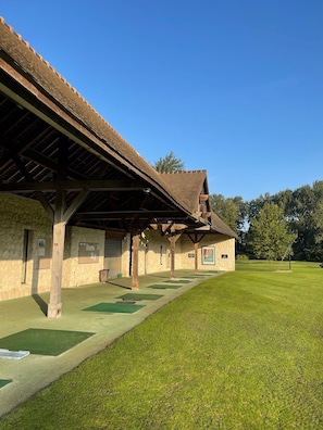 A building with a covered porch and a grassy lawn. - Le Domaine des Vanneaux Golf & Spa L'Isle Adam - MGallery Collection (Presles)