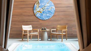 A spa room with wooden panel walls, two wooden chairs, a small round table with a coffee cup, and a large blue and gold artwork.