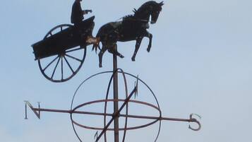 A weather vane with a figure on a horse-drawn carriage.