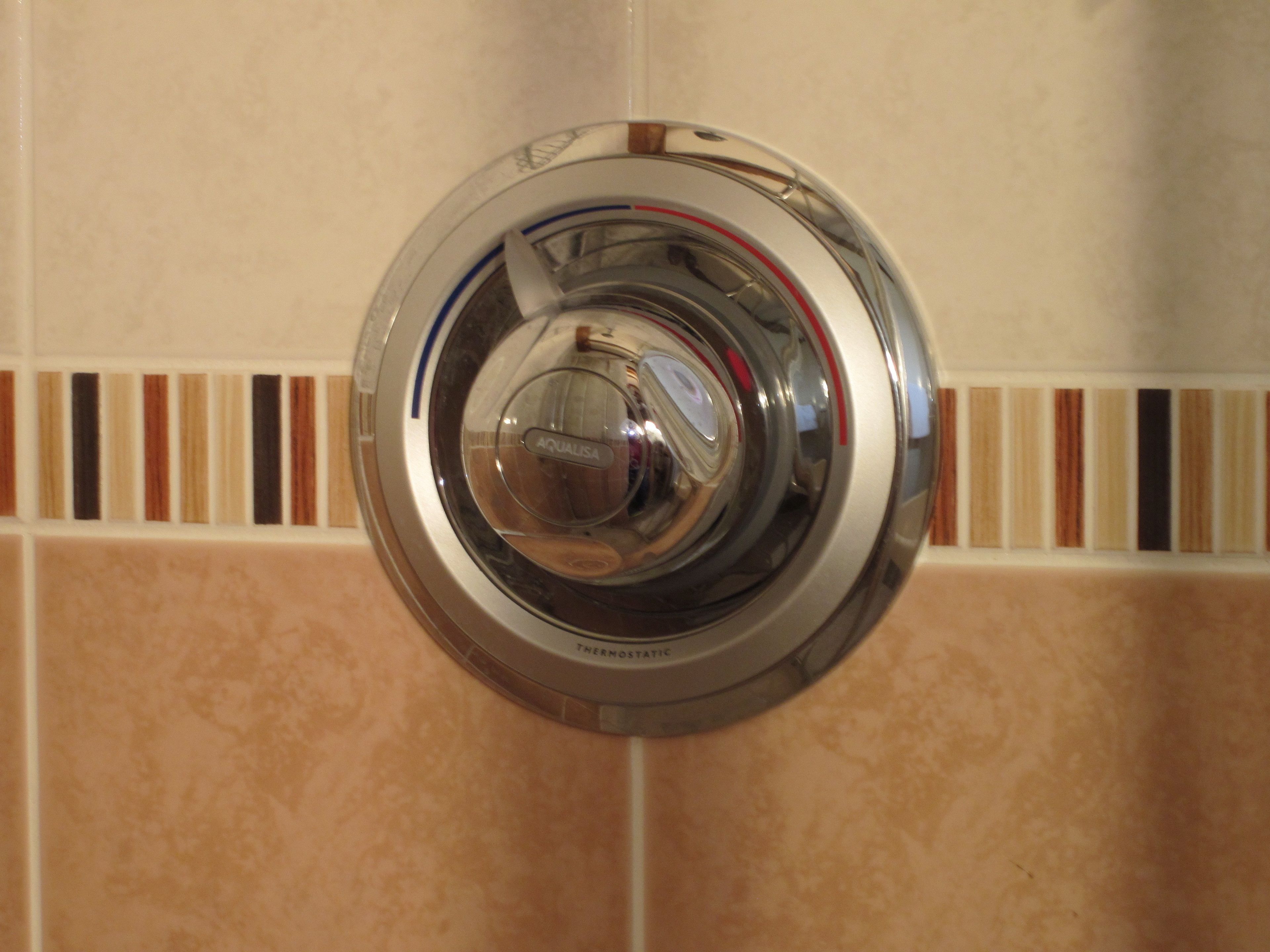 Un baño con un grifo moderno de acero inoxidable y una pared de azulejos con un borde decorativo.