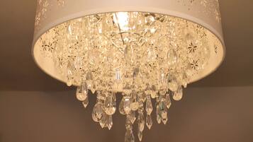 Un lustre composé de nombreux éléments de cristal suspendus à une structure métallique blanche perforée.