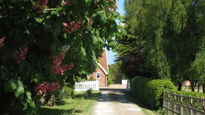 A gravel path leading to a brick building with a white fence. - Colston Hall Farmhouse B&B (Woodbridge)
