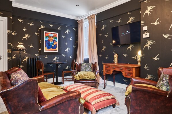 A room with dark walls, a large painting, a television, and leather furniture. - Snug at Clarence (Londonderry)