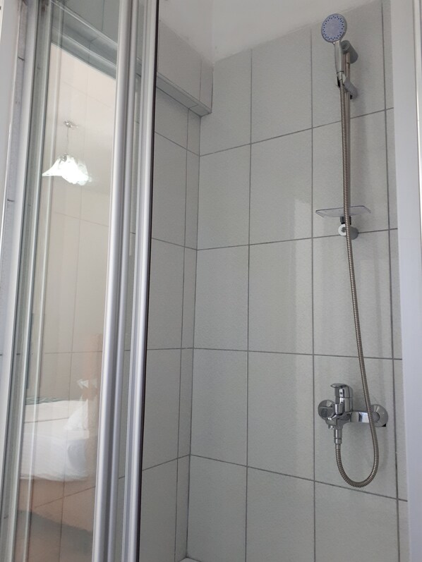 A shower area with a glass door, a handheld showerhead, and a wall-mounted faucet. - San Simon Hotel (Kemer)