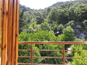 A view from a balcony with a metal railing, overlooking a lush green landscape with trees and a rocky hill in the background. - San Simon Hotel (Kemer)