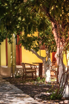 A courtyard with a wooden bench, a table, and a tree. - San Simon Hotel (Kemer)