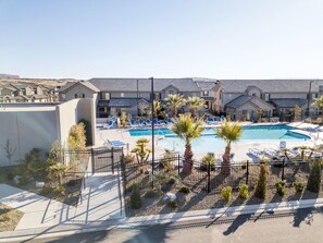 Un área de piscina con varias piscinas, sillas de descanso y palmeras.