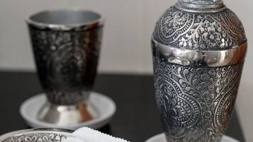 A silver tray with a soap dispenser and a cup on a black table.