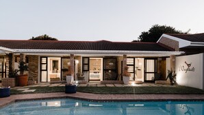 A residential property with a swimming pool, a covered patio, and a brick exterior. - Wagtails Guest House (Gqeberha (Port Elizabeth))