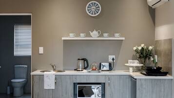 Una cocina moderna con microondas integrado, espacio para café y un reloj en la pared.