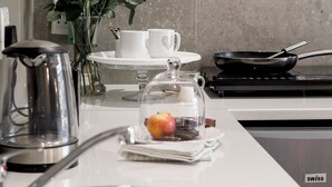 A modern kitchen with a stainless steel sink, a kettle, a frying pan, and a vase with white roses. - Wagtails Guest House (Gqeberha (Port Elizabeth))