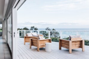 Une terrasse en bois avec deux chaises en bois et une petite table blanche, donnant sur une étendue d’eau.