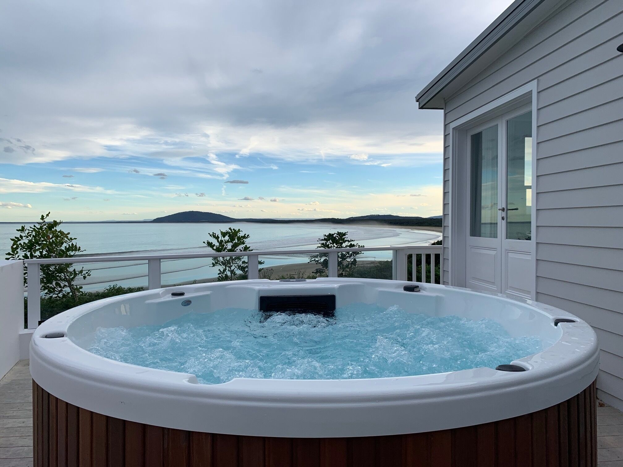 Ein Whirlpool auf einem Balkon mit Blick auf das Meer und eine ferne Insel.
