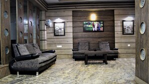 Ein Zimmer mit einer Holzwand, zwei Sofas, einem Fernseher und gerahmten Bildern.