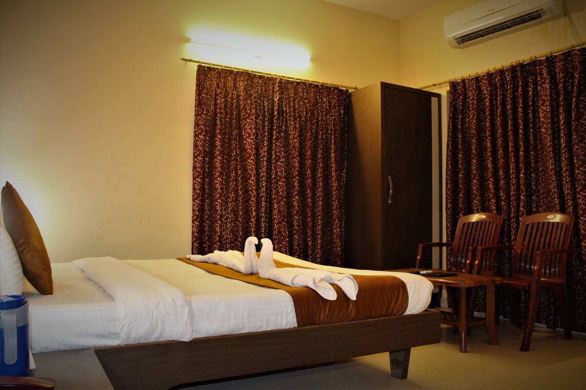 A hotel room with a bed, a chair, a desk, and curtains.