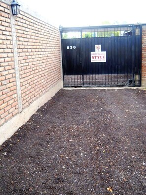 A brick wall with a black metal gate labeled '836 STYLE' and a paved area in front.