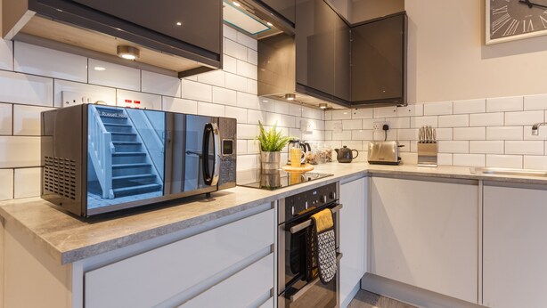 A modern kitchen with a built-in microwave, oven, and a large clock on the wall.