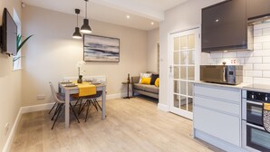 A modern kitchen with a dining area, featuring a microwave, oven, and a dining table with chairs.