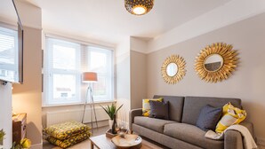 A living room with a sofa, a coffee table, a floor lamp, and decorative mirrors on the wall.