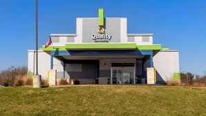 A modern hotel with a prominent 'Quality Inn & Suites' sign, a well-maintained lawn, and a clear blue sky.
