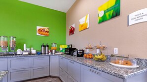 A kitchen with a green wall, a granite countertop, and various breakfast items.