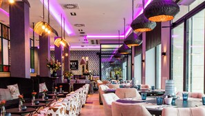 A modern restaurant with a long communal dining area, individual tables, and hanging pendant lights. - NYX Hotel Bilbao by Leonardo Hotels (Bilbao)