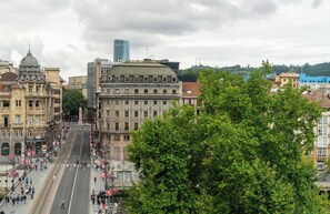 A city street with historic buildings, a tram, and pedestrians. - NYX Hotel Bilbao by Leonardo Hotels (Bilbao)