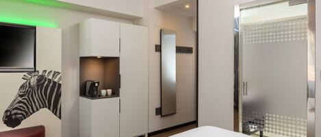 A modern hotel room with a large bed, a wardrobe, a mirror, and a zebra mural on the wall.
