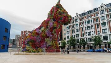 A large floral sculpture resembling a lion in an urban plaza with modern buildings in the background.