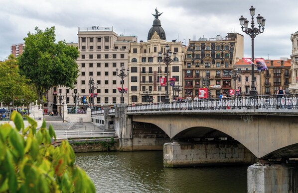 A bridge with a statue on top, surrounded by historic buildings and a river. - NYX Hotel Bilbao by Leonardo Hotels (Bilbao)