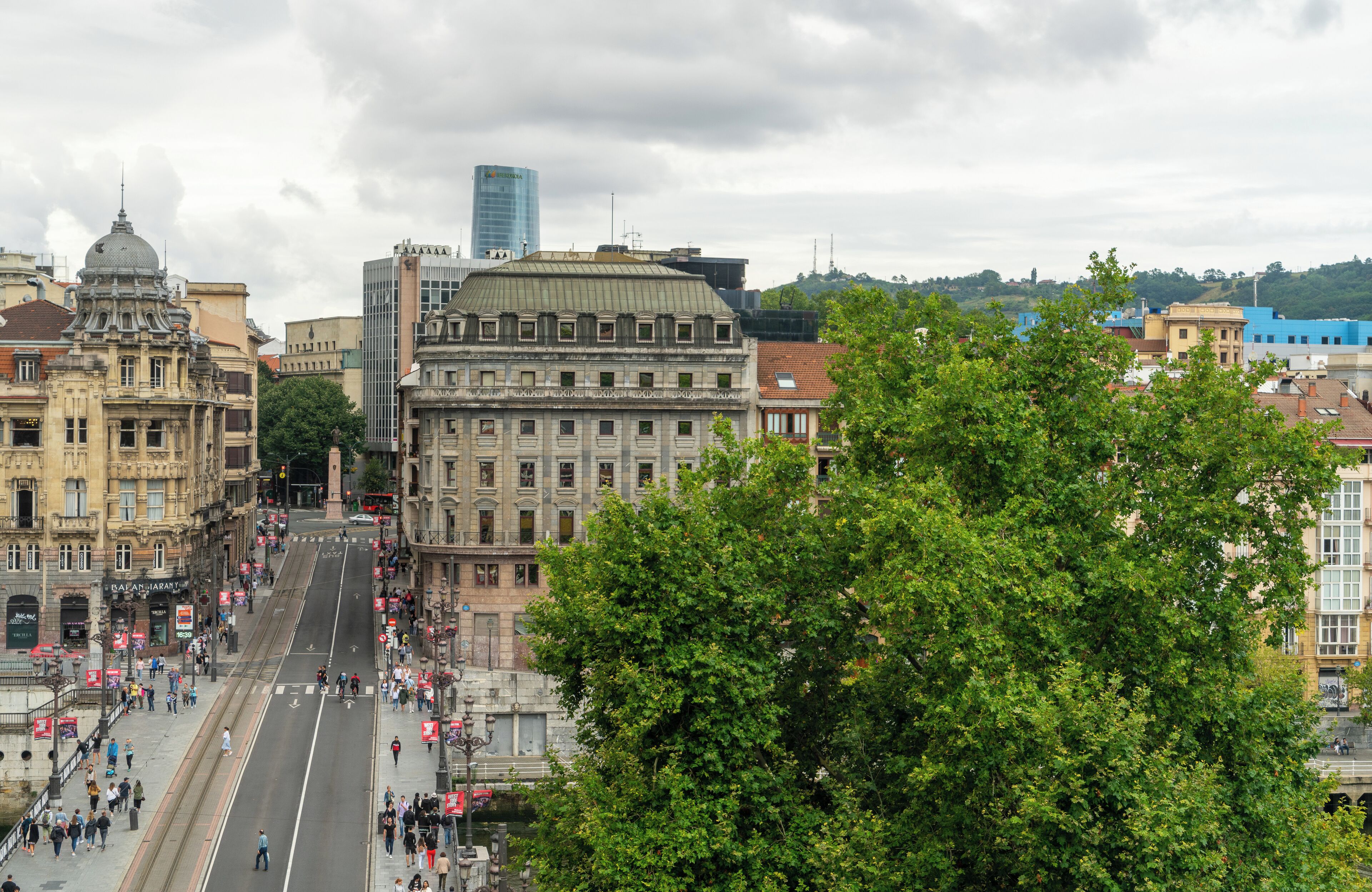 A city street with historic buildings, a tram, and pedestrians.