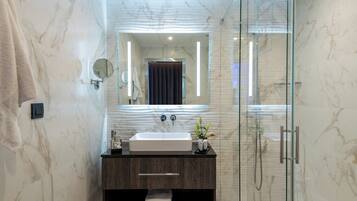 A modern bathroom with a glass-enclosed shower, a marble sink, and a large mirror.