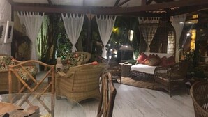 A cozy indoor seating area with wicker furniture and a ceiling fan. - Pousada Bambu Brasil (Alto Paraíso de Goiás)