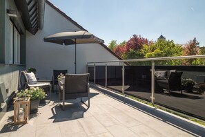 A rooftop terrace with outdoor furniture, a large umbrella, and a view of the cityscape. - Miralior Apartment (Mainz)