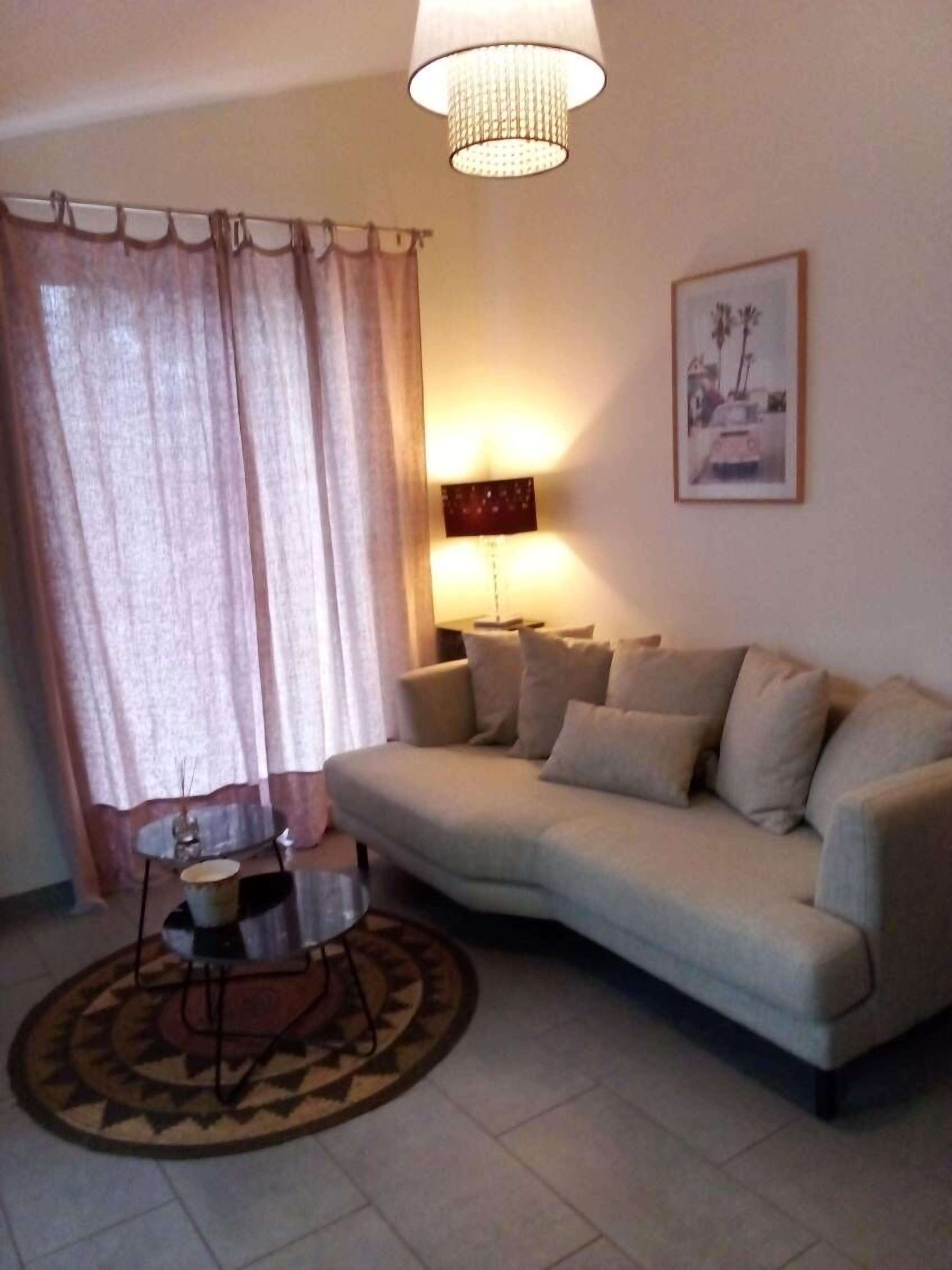 Ein Wohnzimmer mit einem beigen Sofa, einem runden Couchtisch, einer Lampe und einem gerahmten Bild an der Wand.
