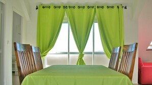 Habitació amb llit, dues cadires de fusta, una cadira vermella i una finestra amb cortines verdes.