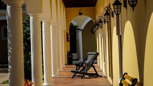 A covered corridor with white columns, benches, and wall-mounted lanterns. - Hotel Hacienda Izamal (Izamal)