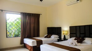 A hotel room with two beds, a window with curtains, a nightstand with a lamp, and a ceiling fan. - Hotel Hacienda Izamal (Izamal)