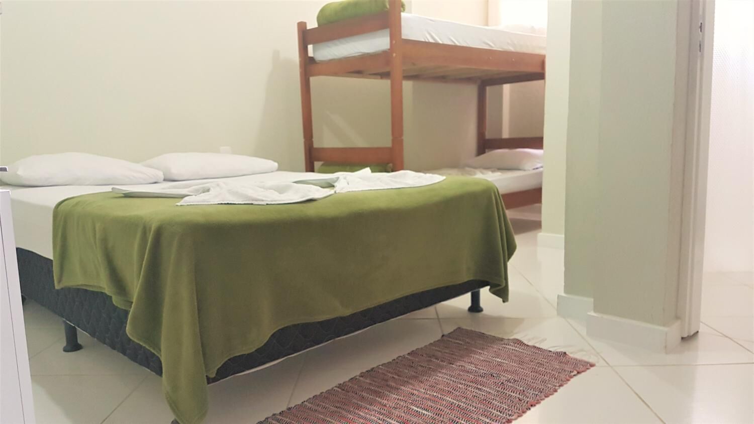 A room with a bunk bed, a single bed, and a green bedspread.